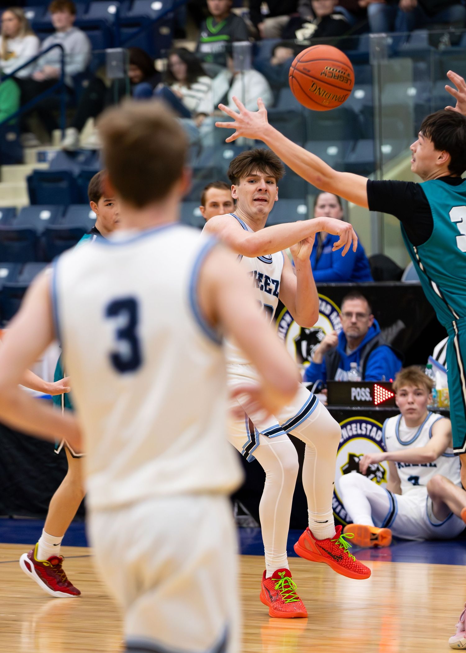 Breeze player #14 passes ball while being defended during high school basketball game.