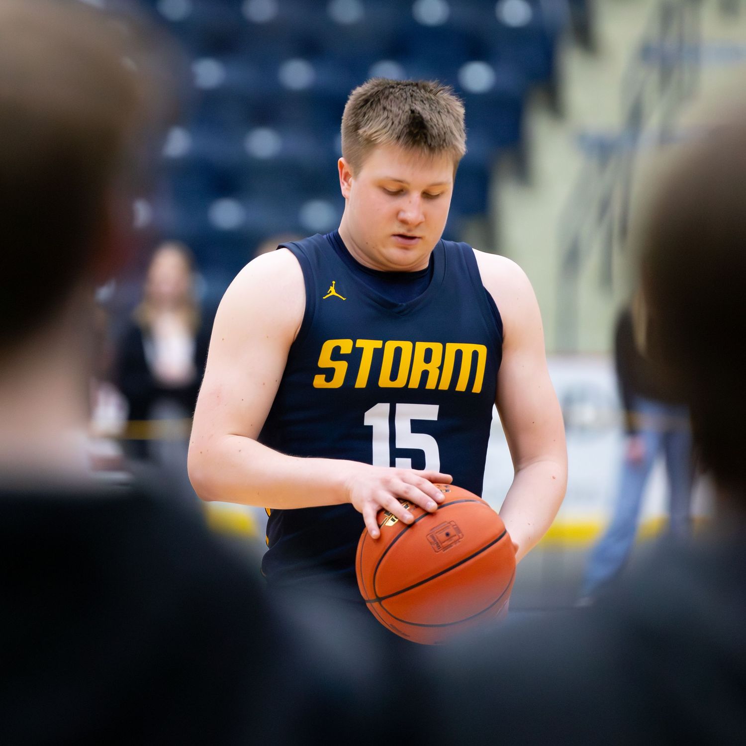 Storm basketball player number 15 focuses while preparing free throw during indoor basketball game.