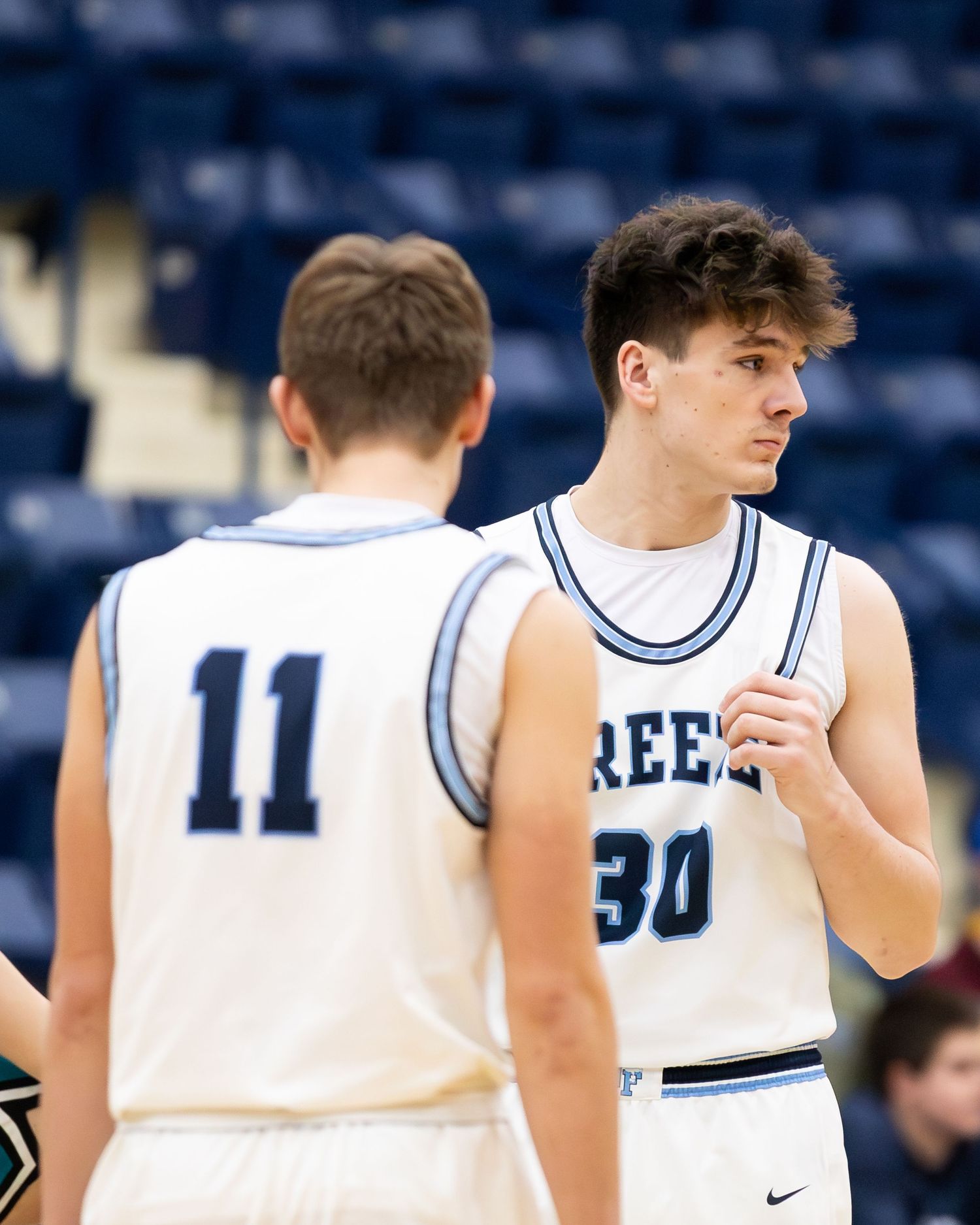 Two Breeze basketball players #11 and #30 in white Nike uniforms during game timeout.