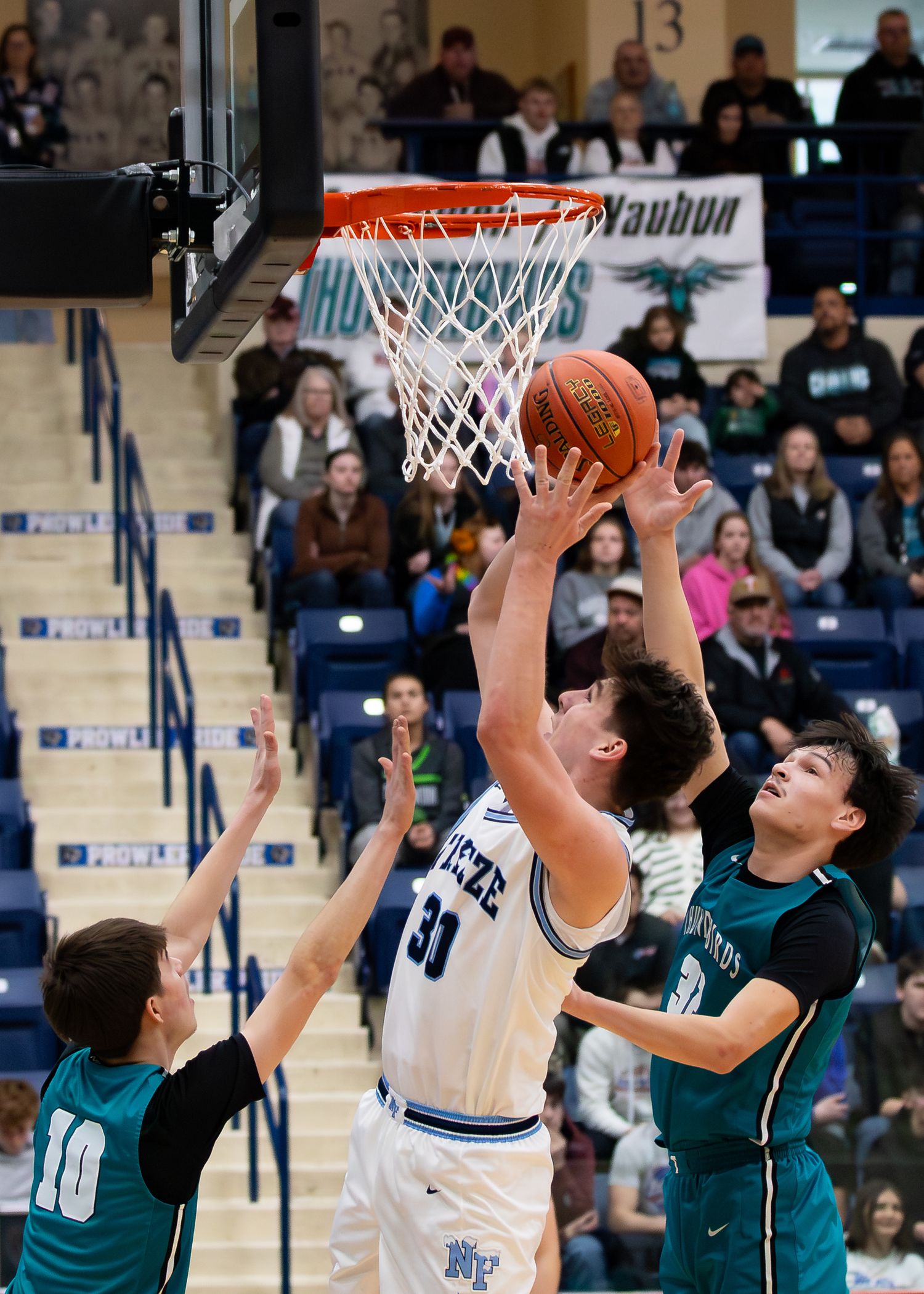 Player #31 in white Breeze jersey drives to basket against two teal-uniformed defenders.