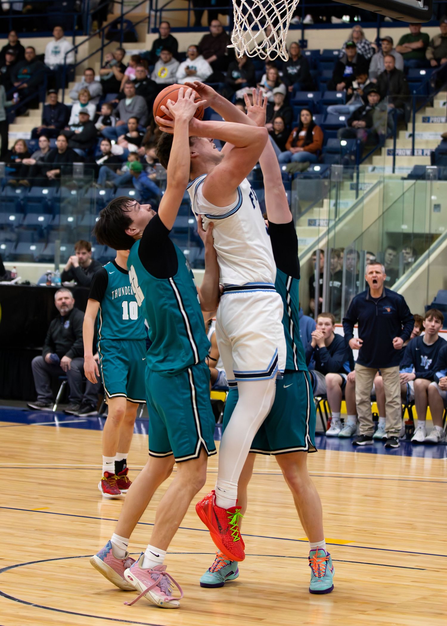 Breeze player battles for rebound against defender #10 in teal jersey during basketball game.