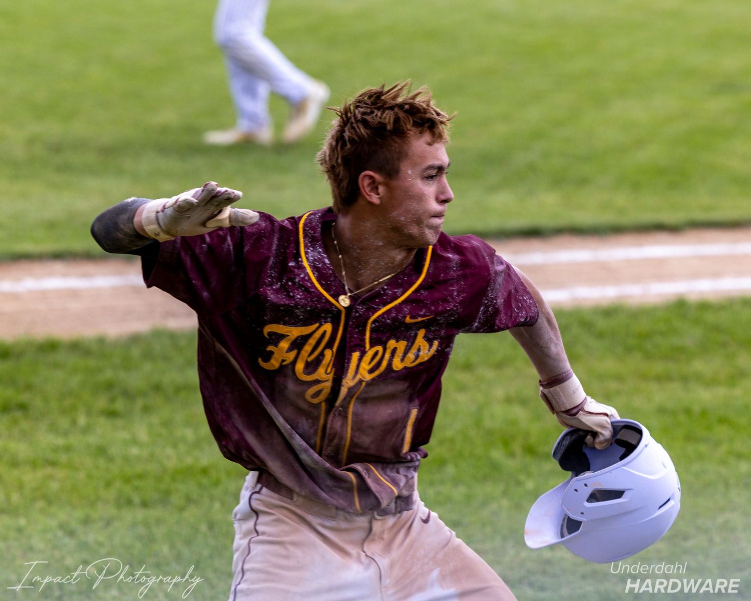 Baseball player in Flyers uniform running bases, holding helmet, uniform dirty from sliding.