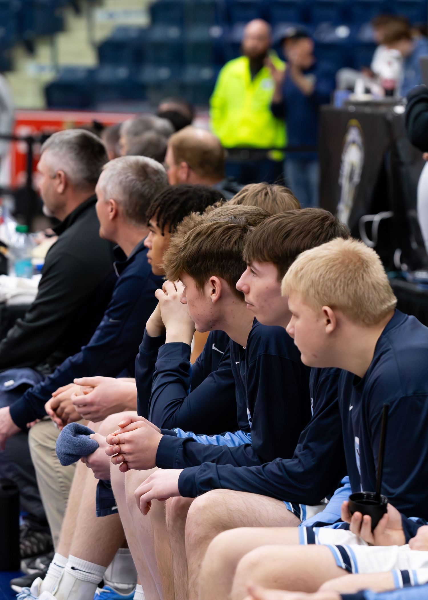 Breeze basketball team players sit attentively on bench during high school tournament game.