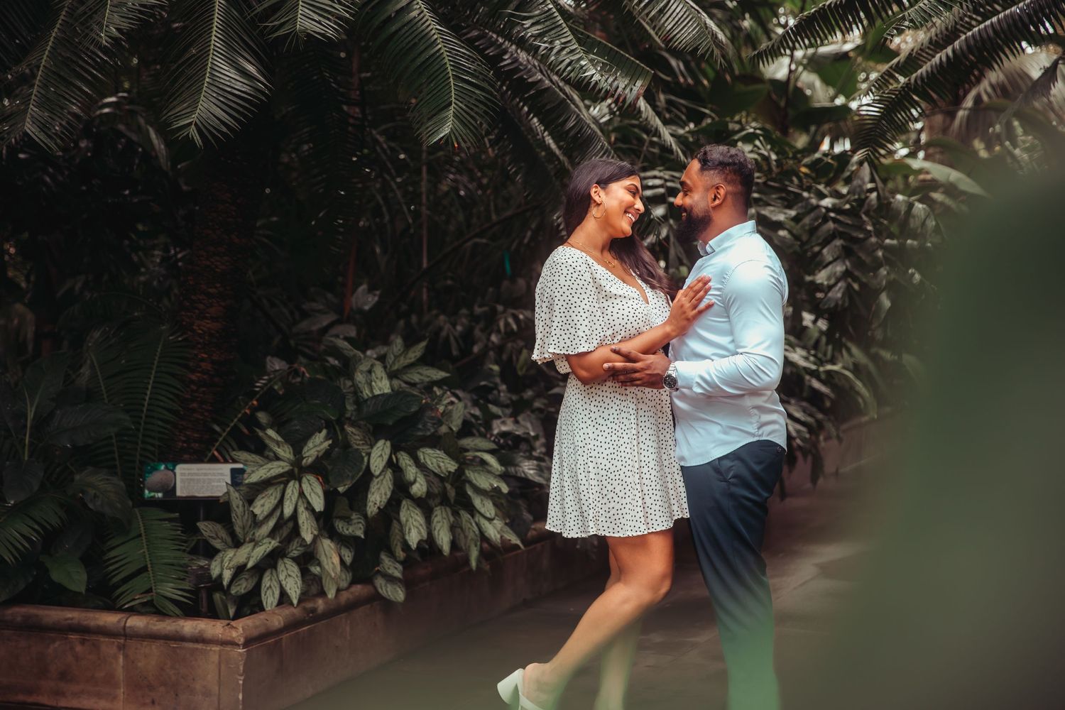 Couple sharing a romantic moment surrounded by lush tropical greenery.