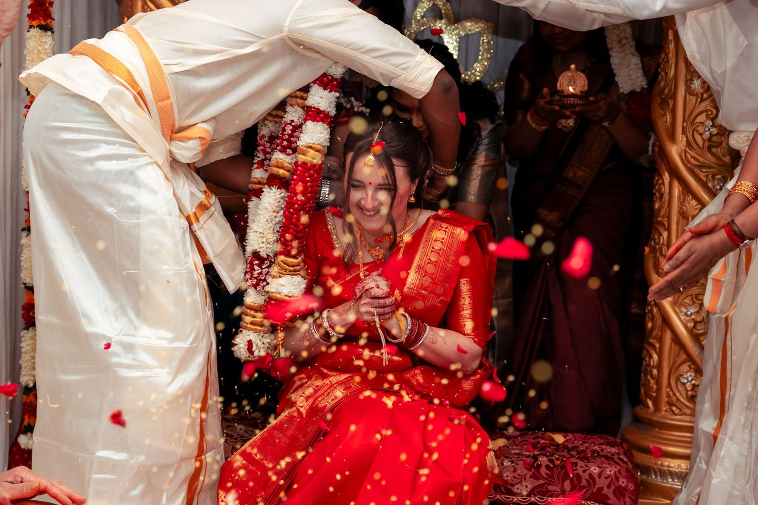Indian bride in red lehenga smiling during traditional Hindu wedding ceremony.
