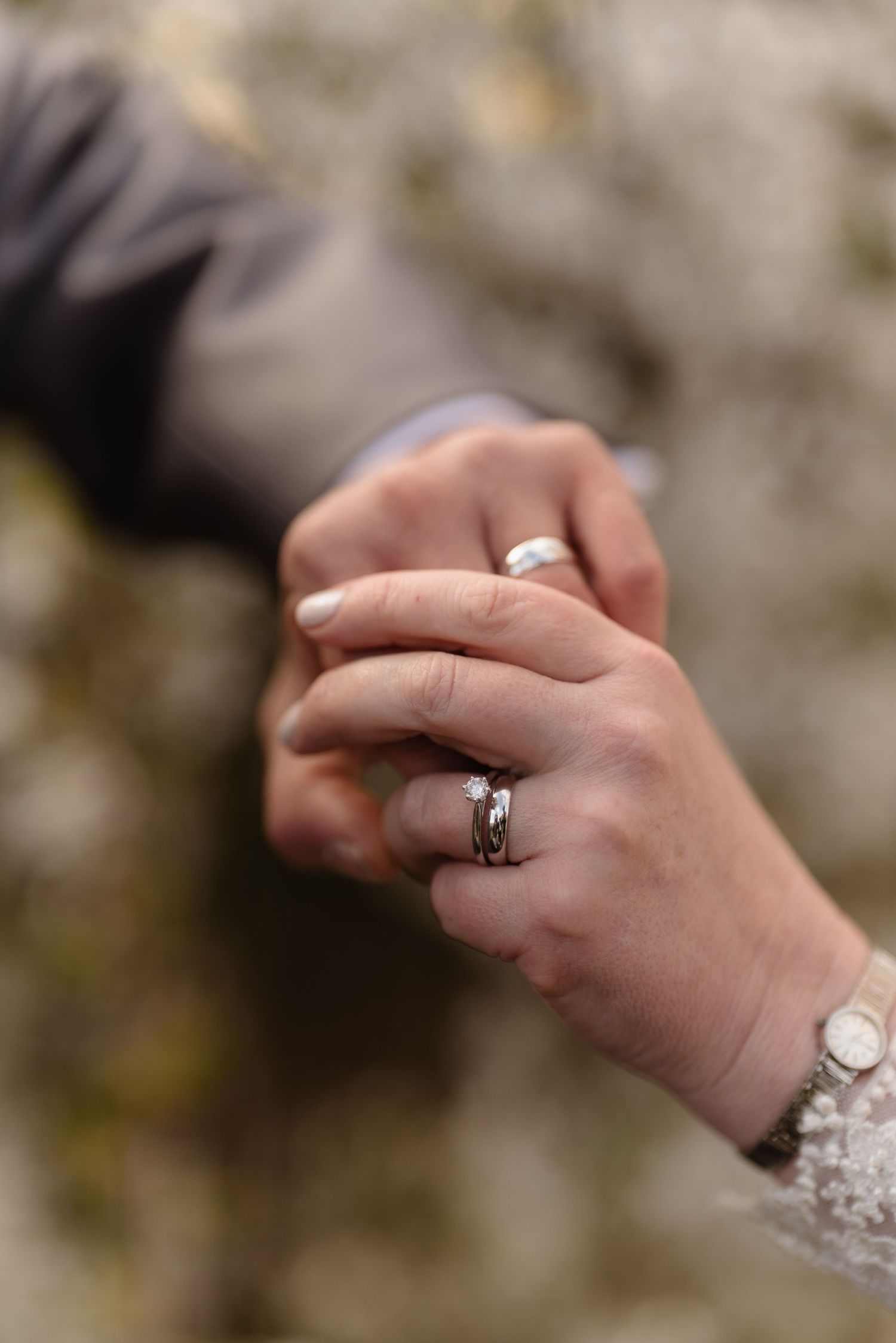Close-up of couple holding hands wearing wedding and engagement rings, symbolizing marriage and commitment.