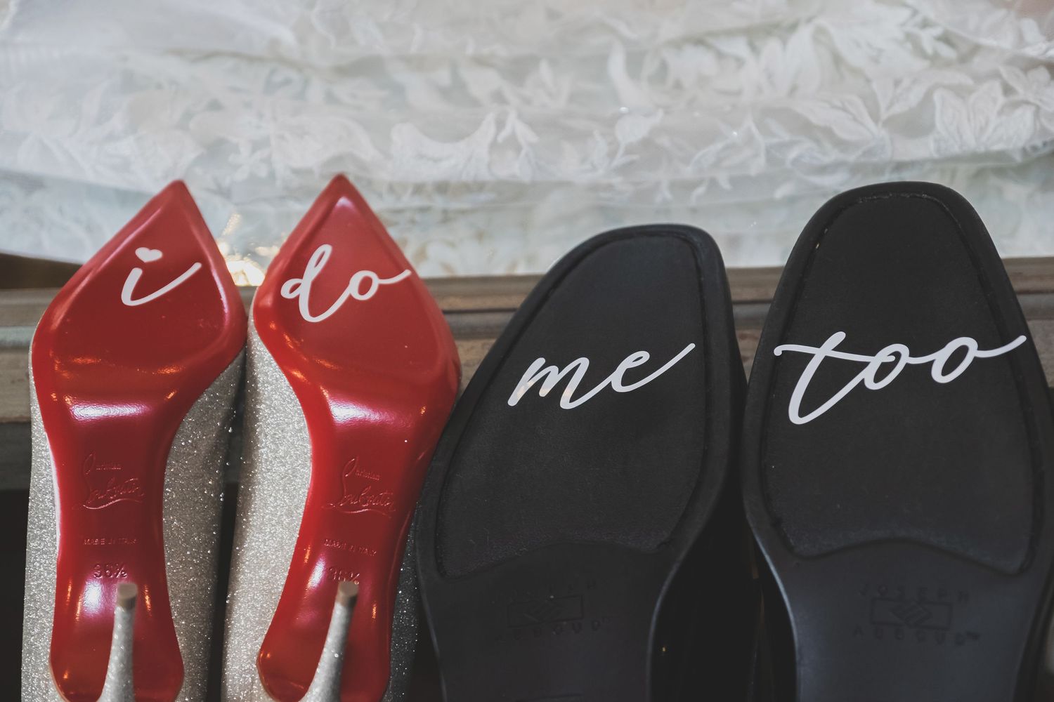 Bridal red heels and groom black loafers with I do and me too written on the soles.