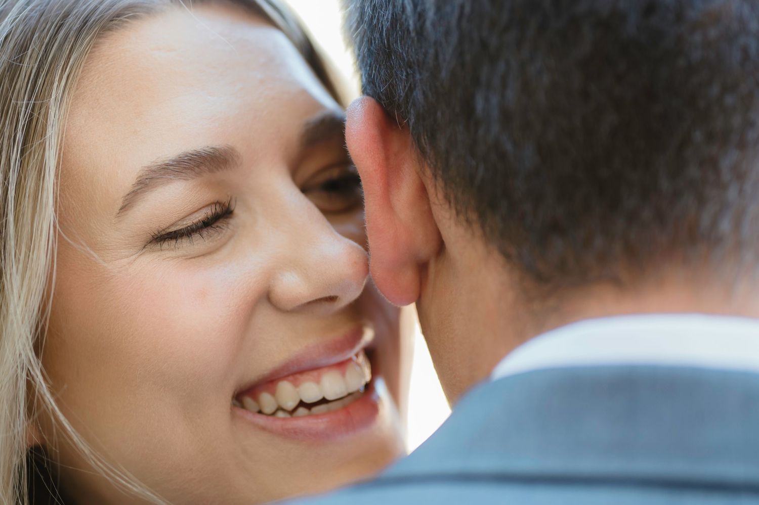 Close-up of a smiling woman leaning in close to her partner in a tender romantic moment.