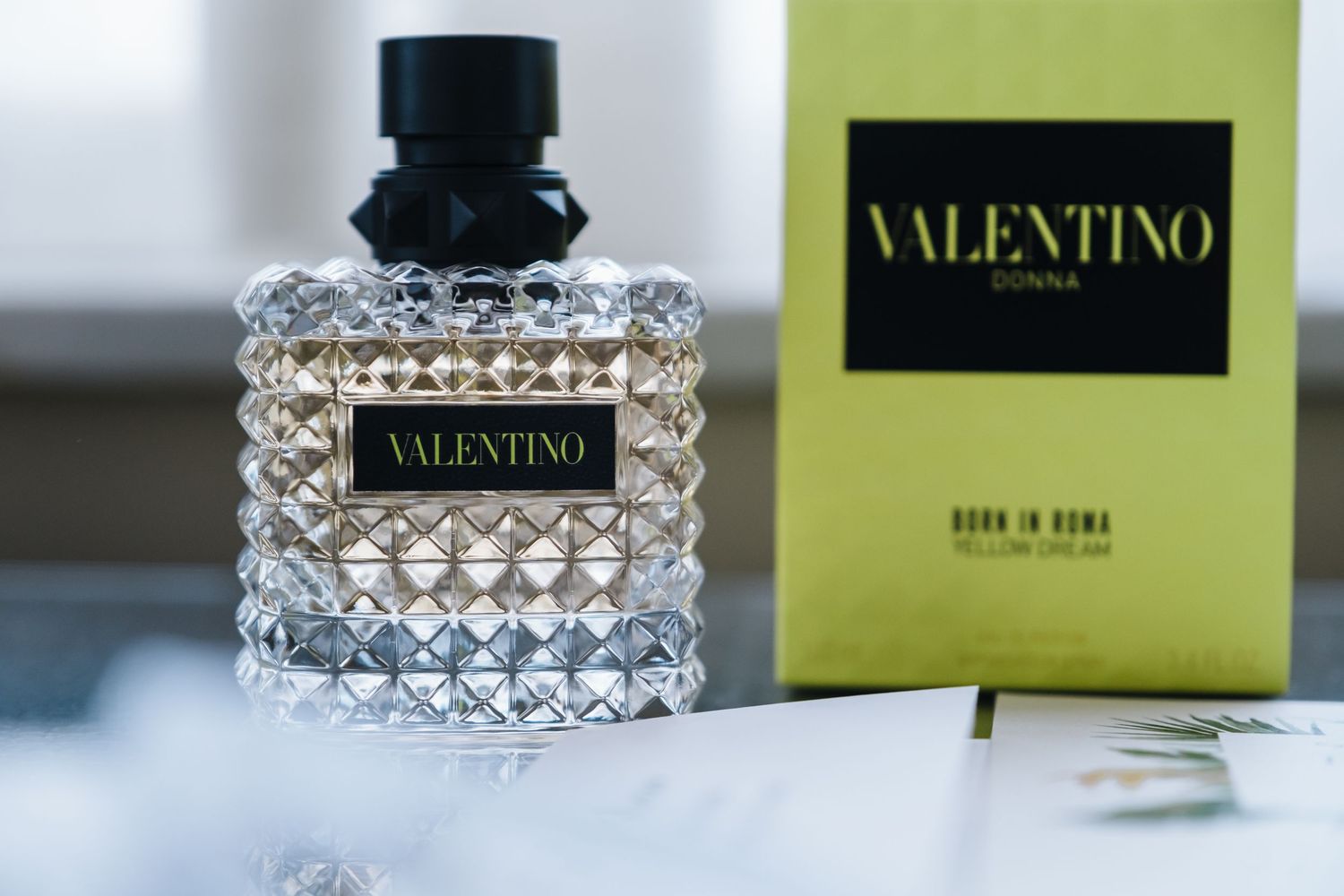 Valentino Donna Born in Roma Yellow Dream perfume bottle beside green box on table.