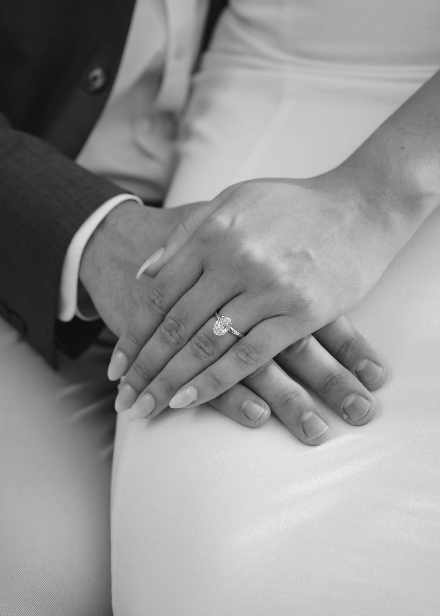 Close-up of bride and groom hands with elegant diamond engagement ring on wedding day.