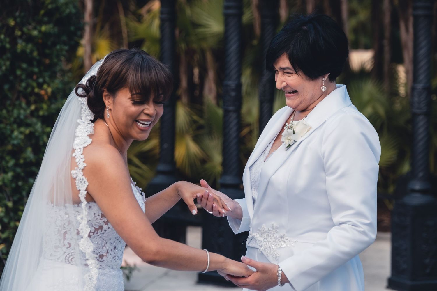 Bride in lace wedding dress laughing joyfully with officiant dressed as Elvis at wedding.