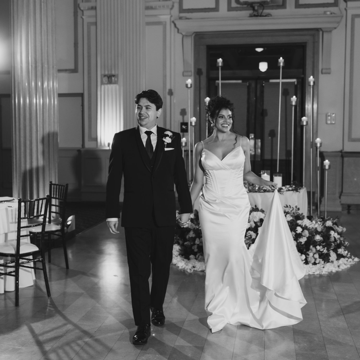 Black and white photo of a bride and groom walking together for the ballroom first look