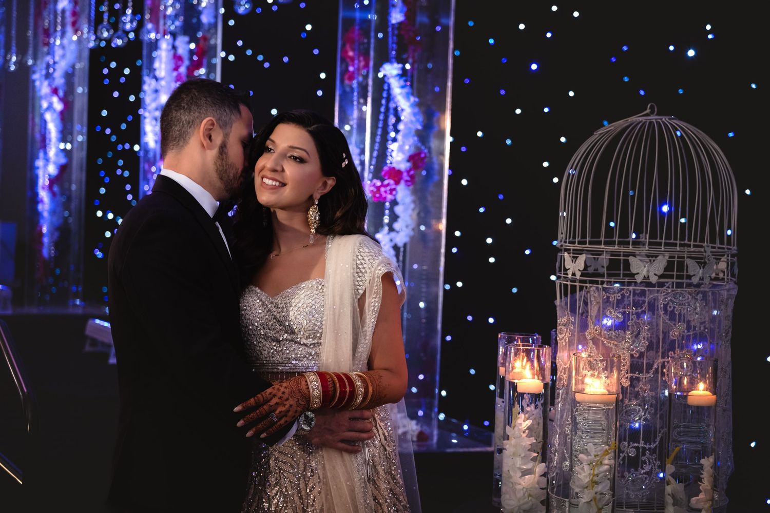 Bride and groom sharing a tender embrace surrounded by sparkling lights and elegant decor at their wedding reception.