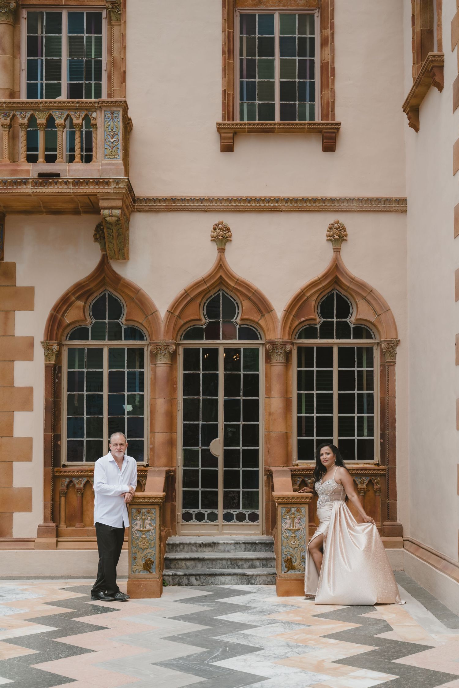 Elegant couple posing before Gothic arched windows at the historic Ringling Museum courtyard in Sarasota.