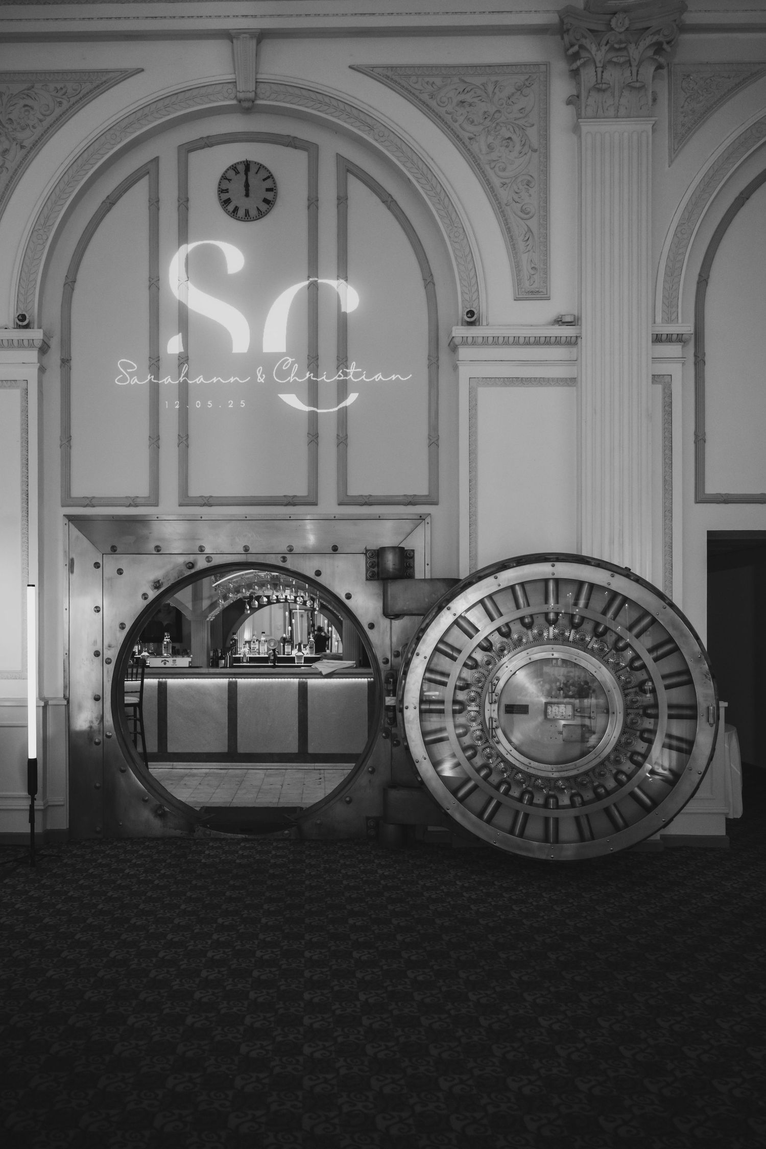 Black and white photo of elegant bank vault bar with SC monogram wedding projection.