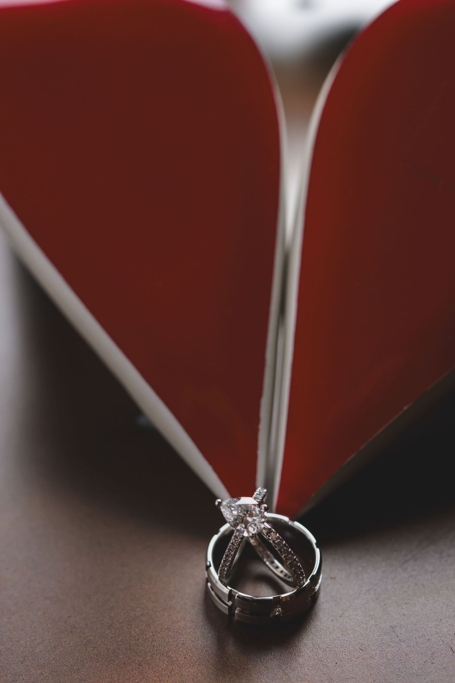 Diamond engagement ring and wedding band resting against red stiletto heel shoes.