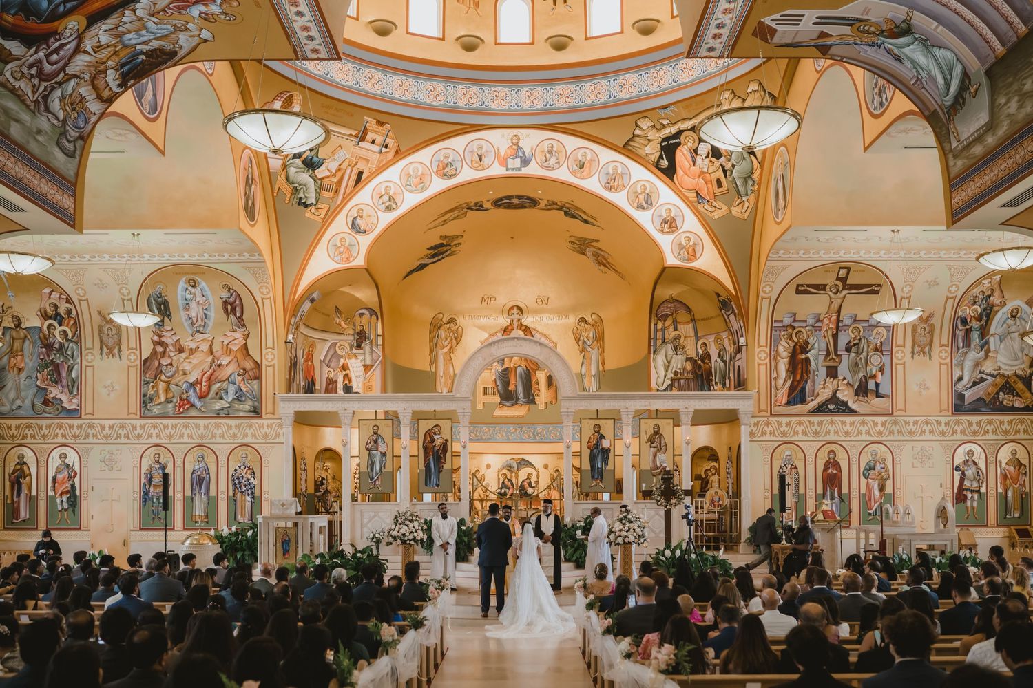 Grand Orthodox church wedding ceremony with ornate golden architecture and full congregation of guests.