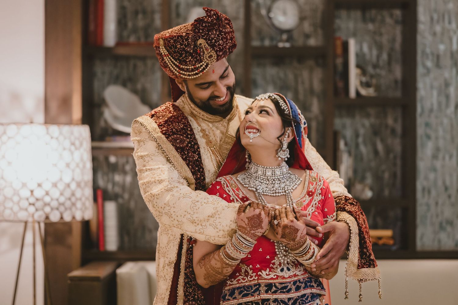 Indian bride and groom in traditional wedding attire sharing a joyful moment during their Hindu wedding ceremony.