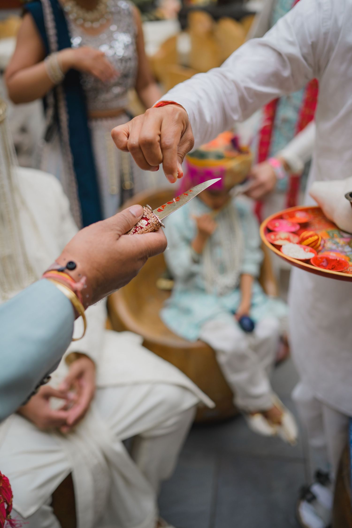 Close-up of hands exchanging a ring during an Indian wedding ritual ceremony.