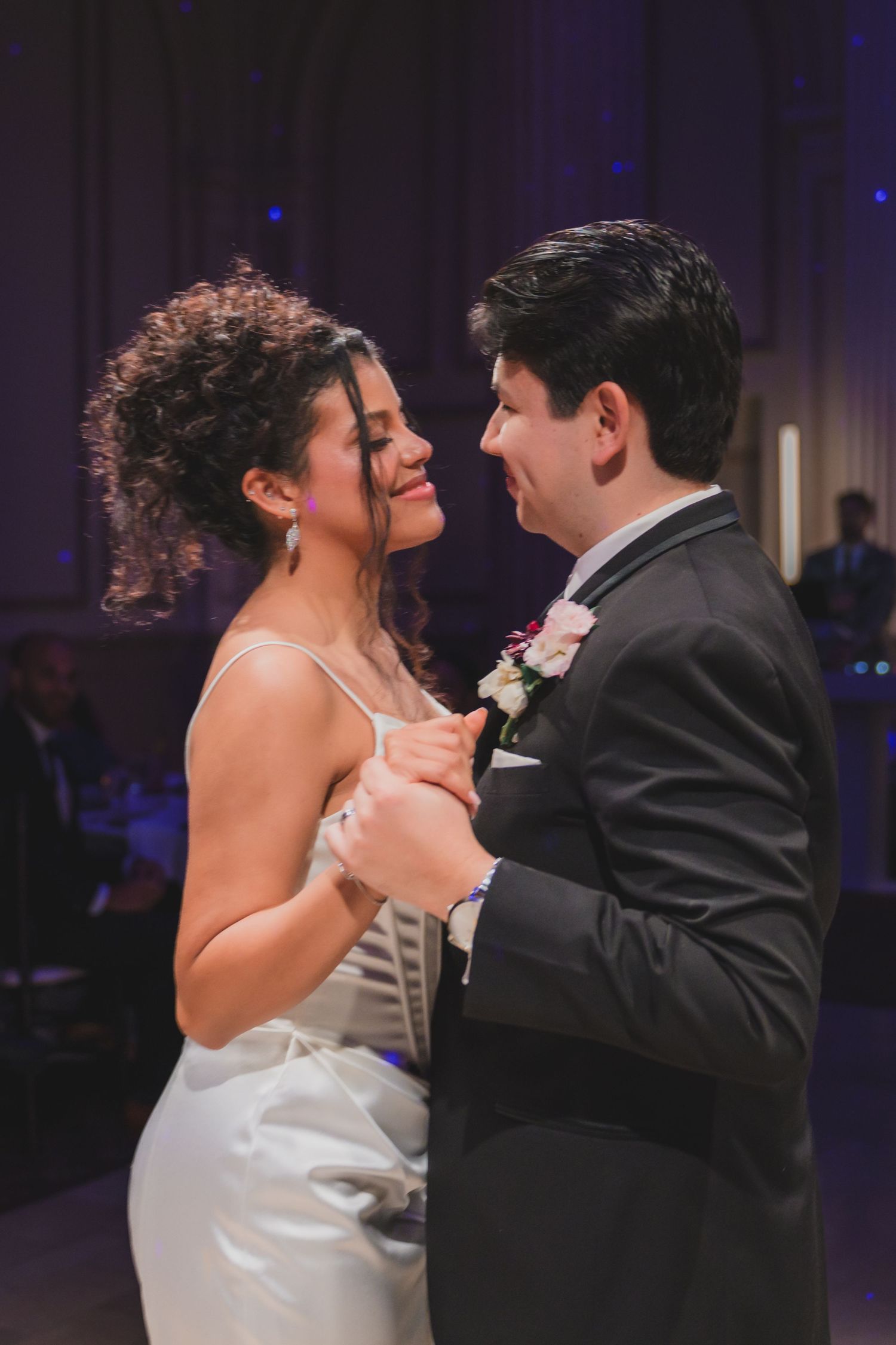 Bride and groom share their first dance, gazing into each other's eyes at a romantic wedding reception.