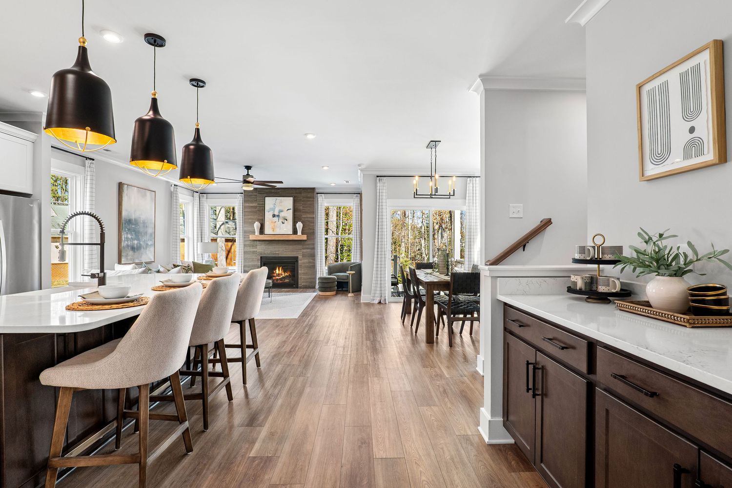 Modern open concept kitchen with pendant lights, upholstered bar stools, and hardwood flooring.