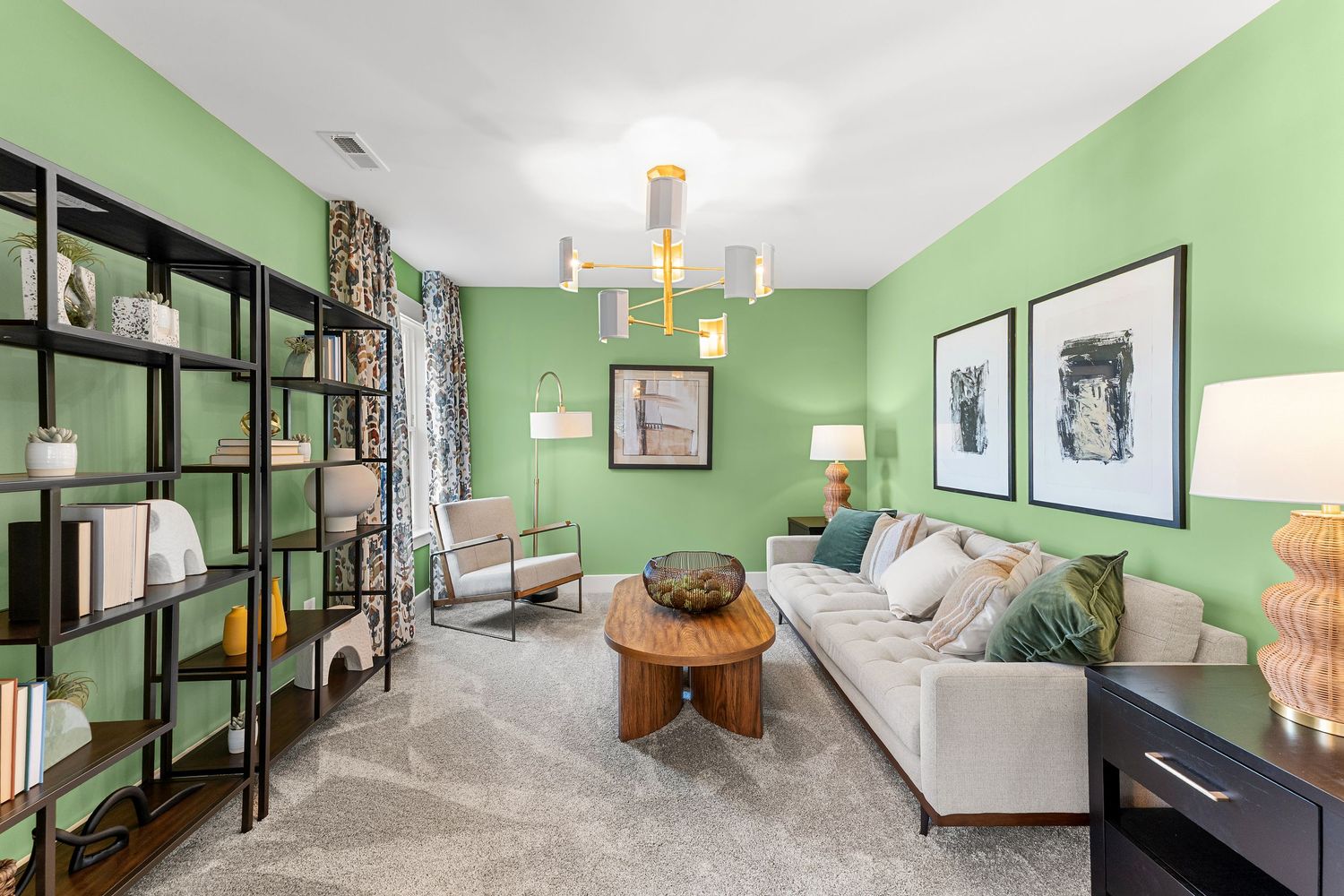 Modern living room with mint green walls, white sectional sofa, black metal shelving units and round wooden coffee table.