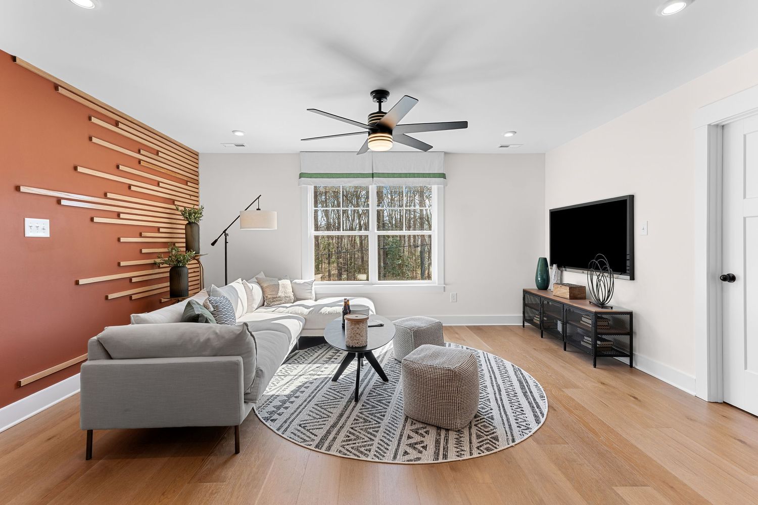 Modern living room with gray sectional sofa, geometric wall art, and hardwood floors featuring a round area rug.