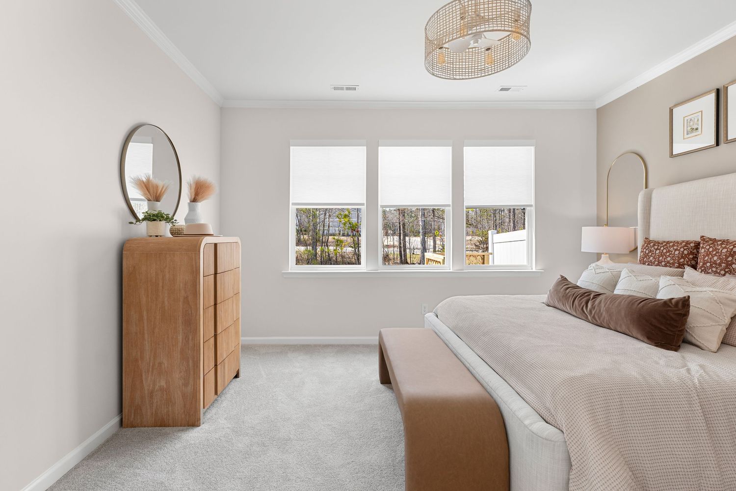 Spacious bedroom with natural light, white walls, and wooden furniture.