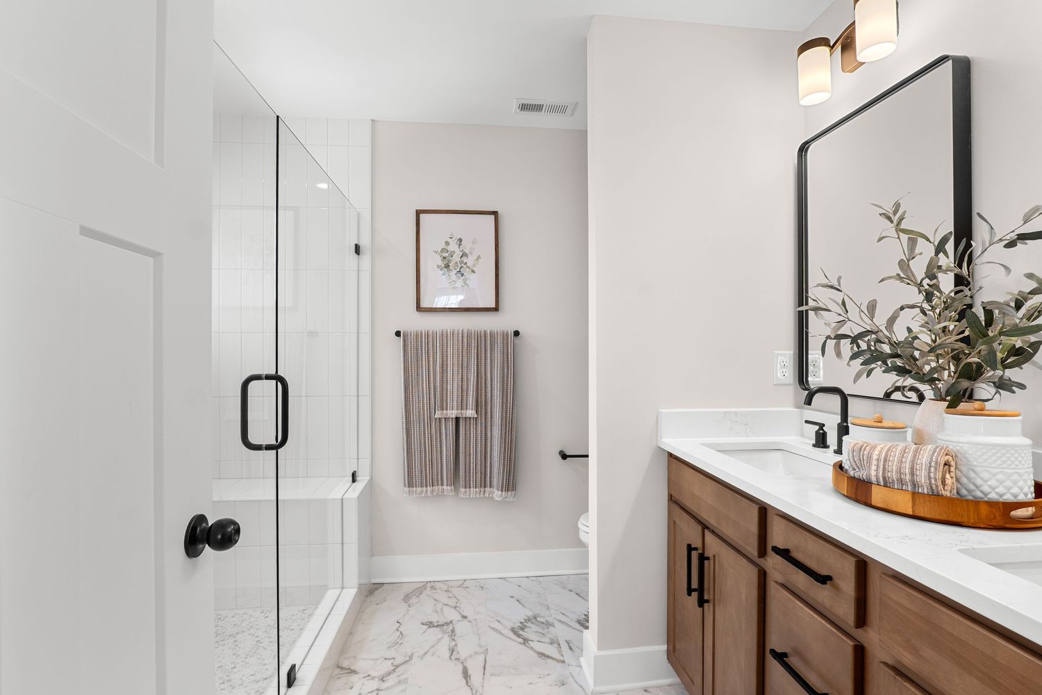 Modern bathroom with white marble countertop, dark wood vanity, and black hardware accents.