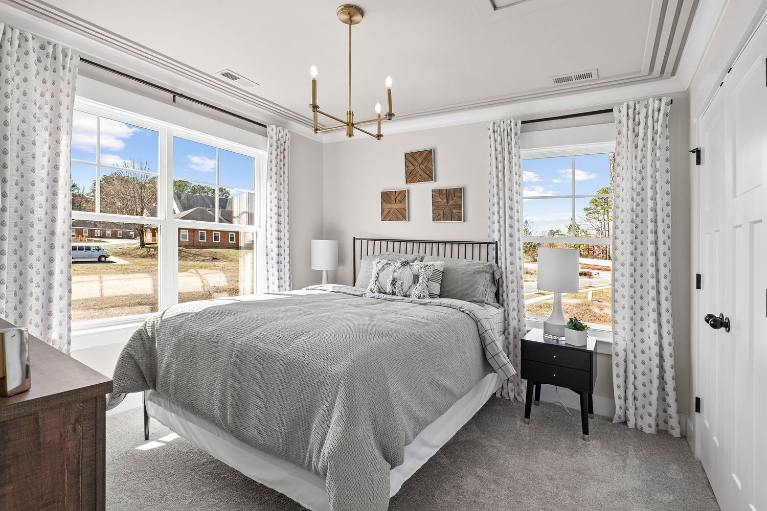 Bright bedroom with white curtains, modern lighting fixtures, and large windows offering natural light.