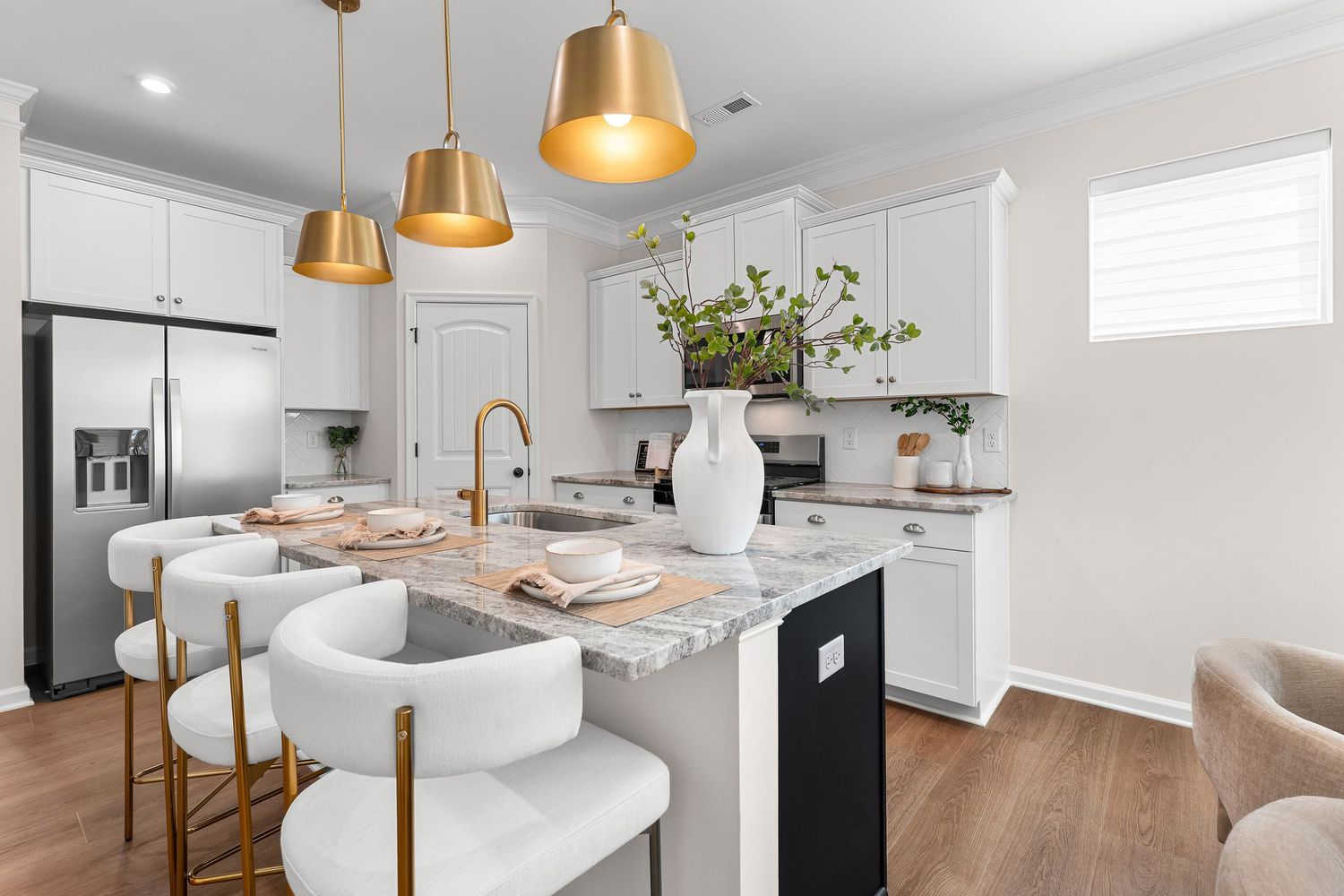 Contemporary white kitchen with gold pendant lights, marble countertops, and sleek cabinetry design.
