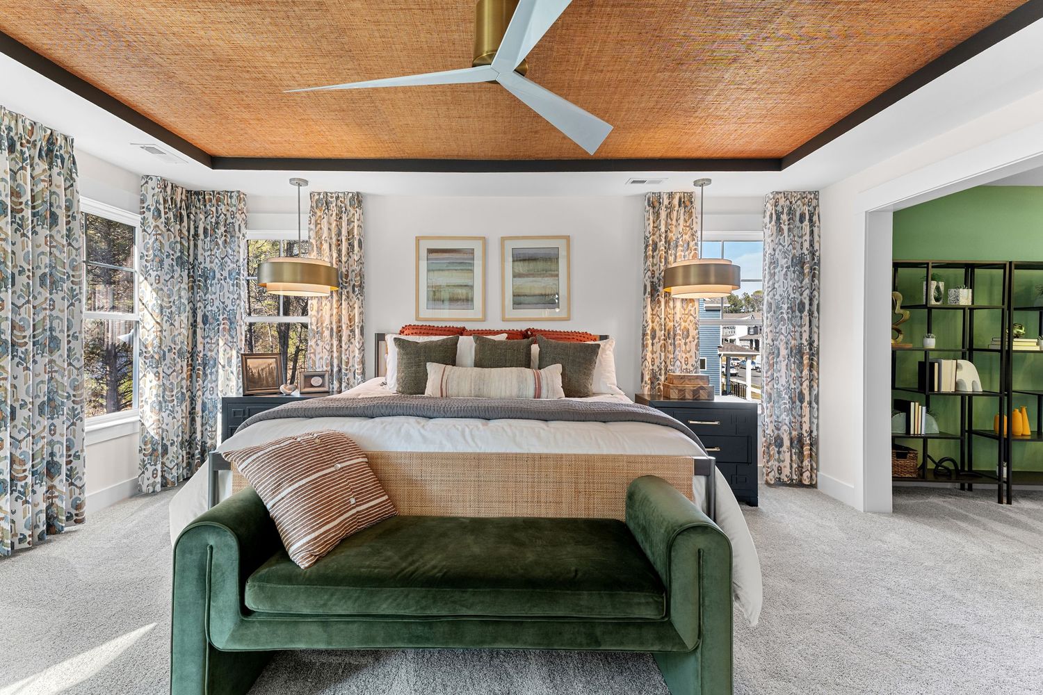 Modern living room features wood paneled ceiling, green velvet sofa, and large windows with patterned curtains.