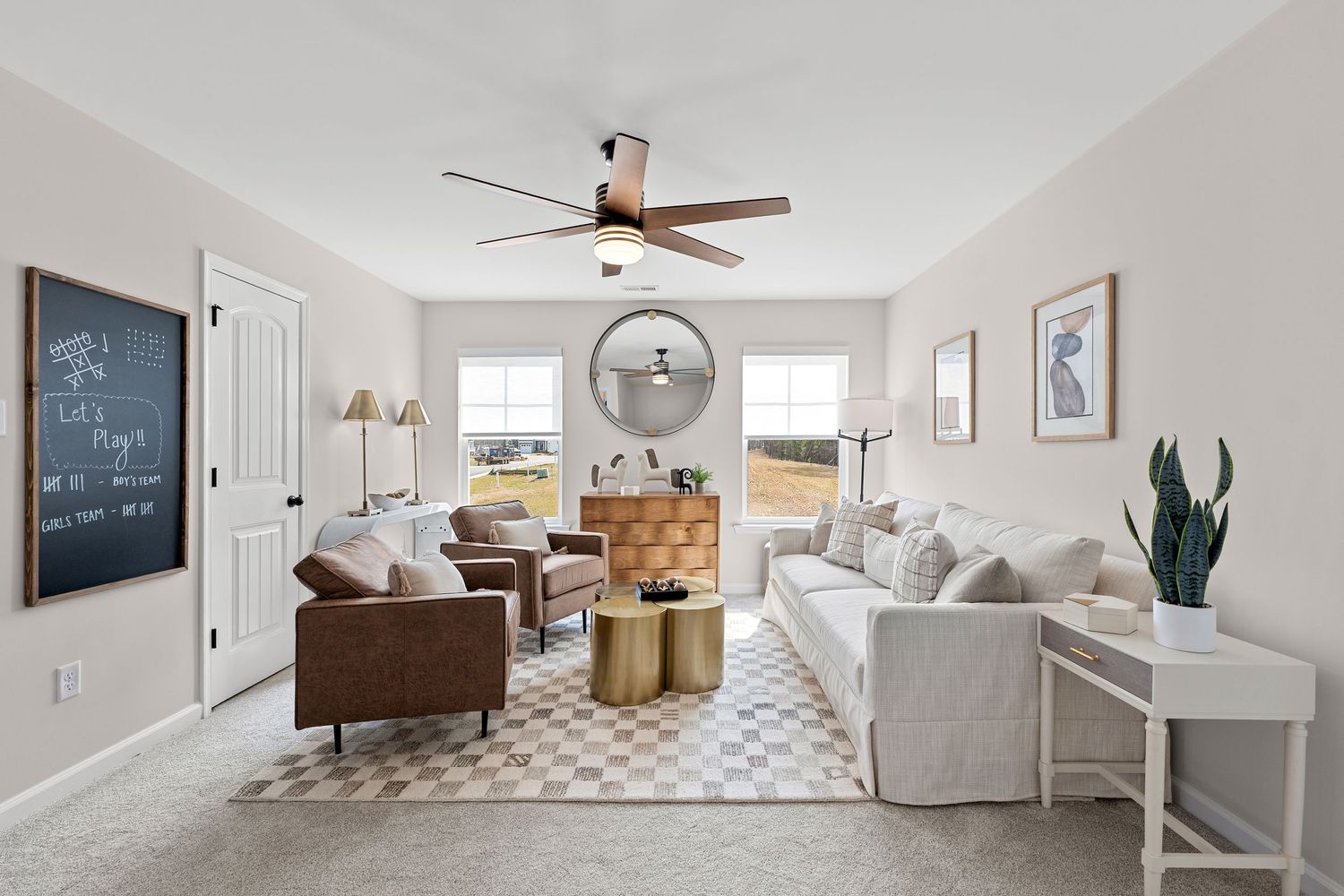 Bright living space with white walls, ceiling fan, and comfortable seating arrangement near mounted TV.