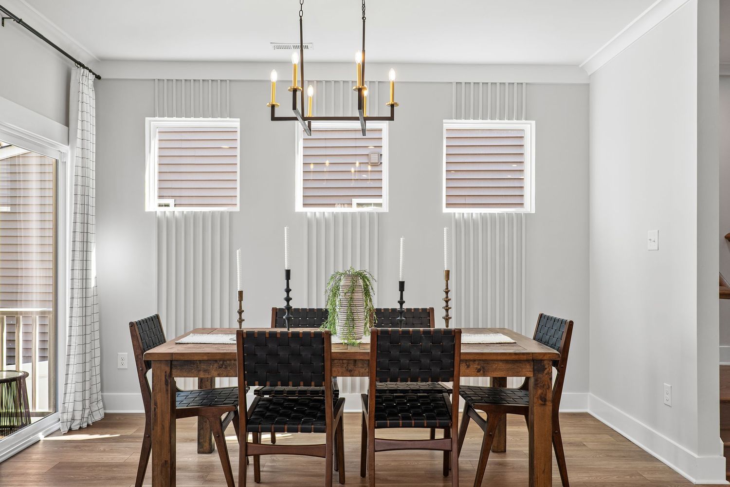 Modern dining room with black chairs, wooden table, and contemporary lighting fixture.