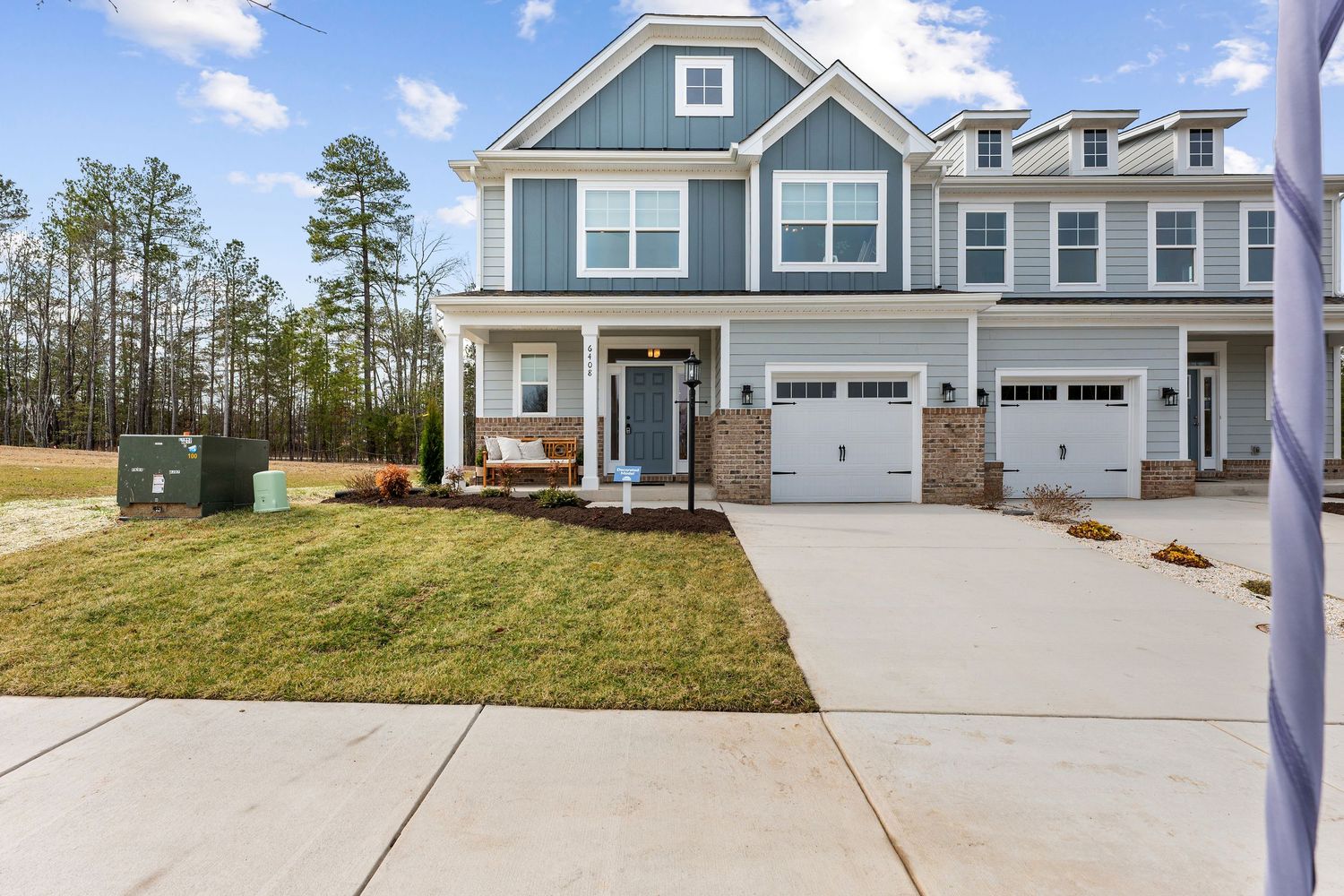 Blue and white two-story house with attached garage and manicured front lawn.