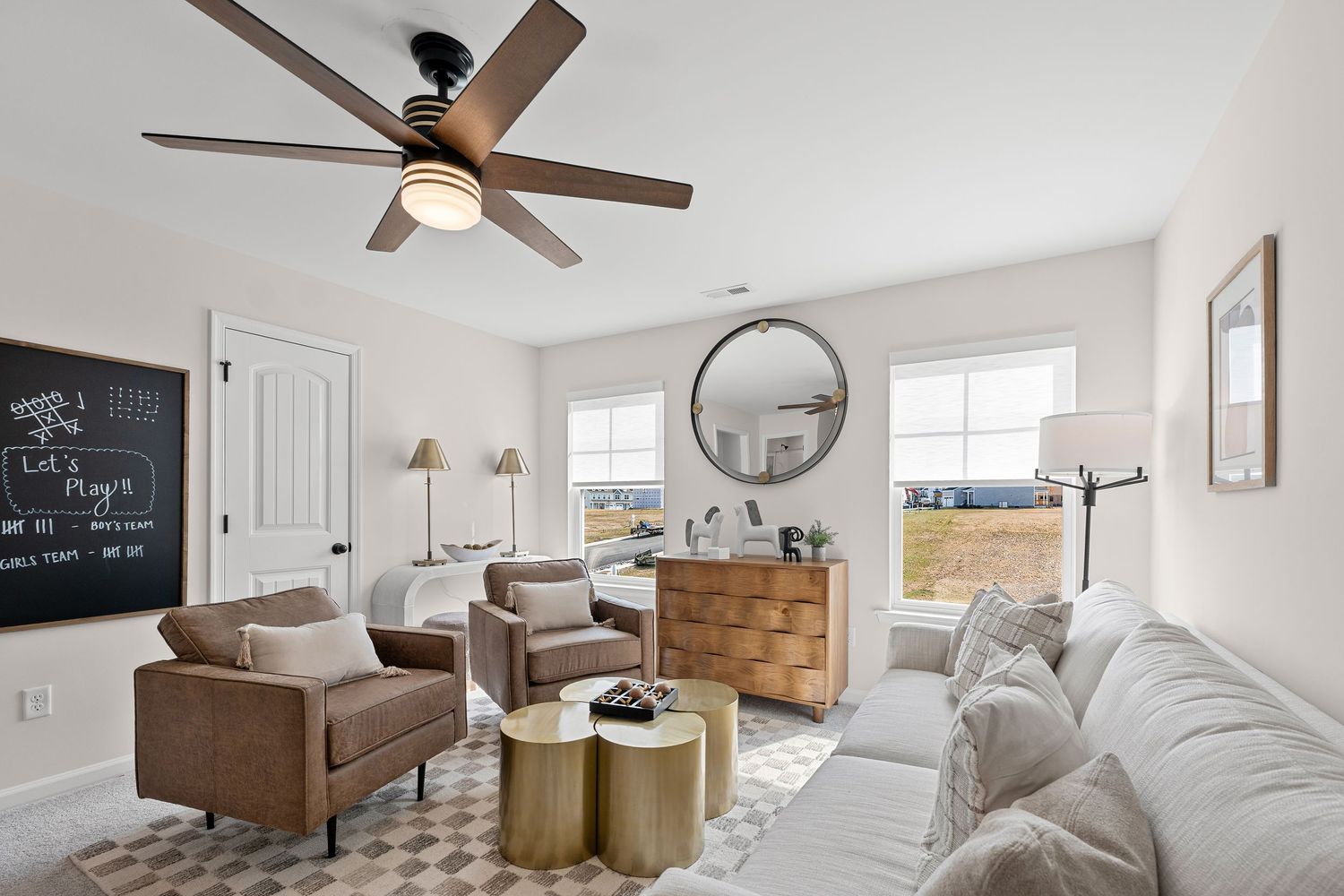 Contemporary living area with ceiling fan, brown leather furniture, and white walls.
