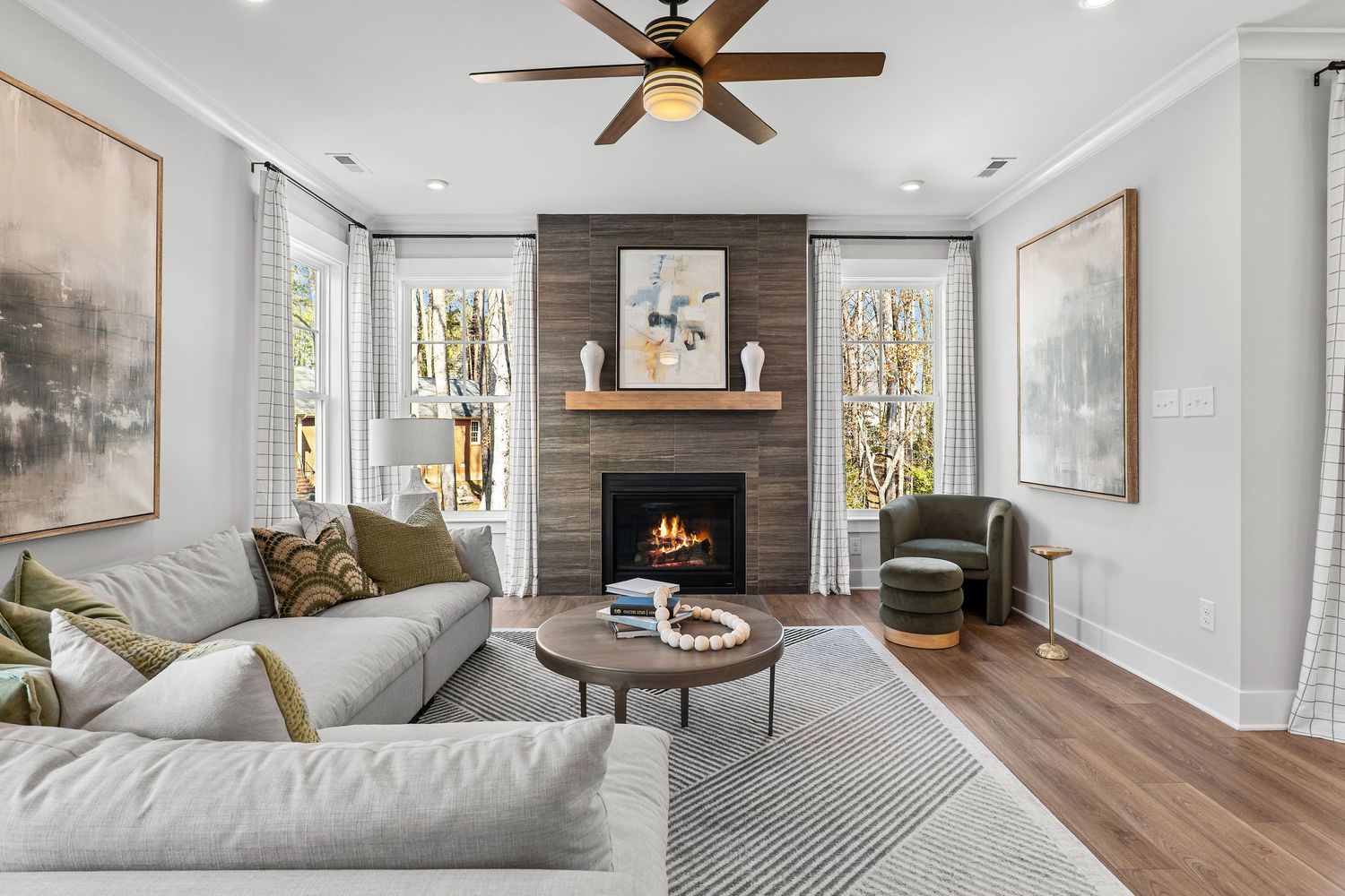 Cozy living room with stone fireplace, gray sectional sofa, and modern artwork flanking the mantel.