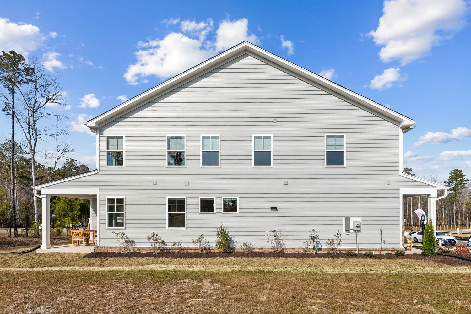 Side view of large white two-story duplex with covered porch and multiple windows.