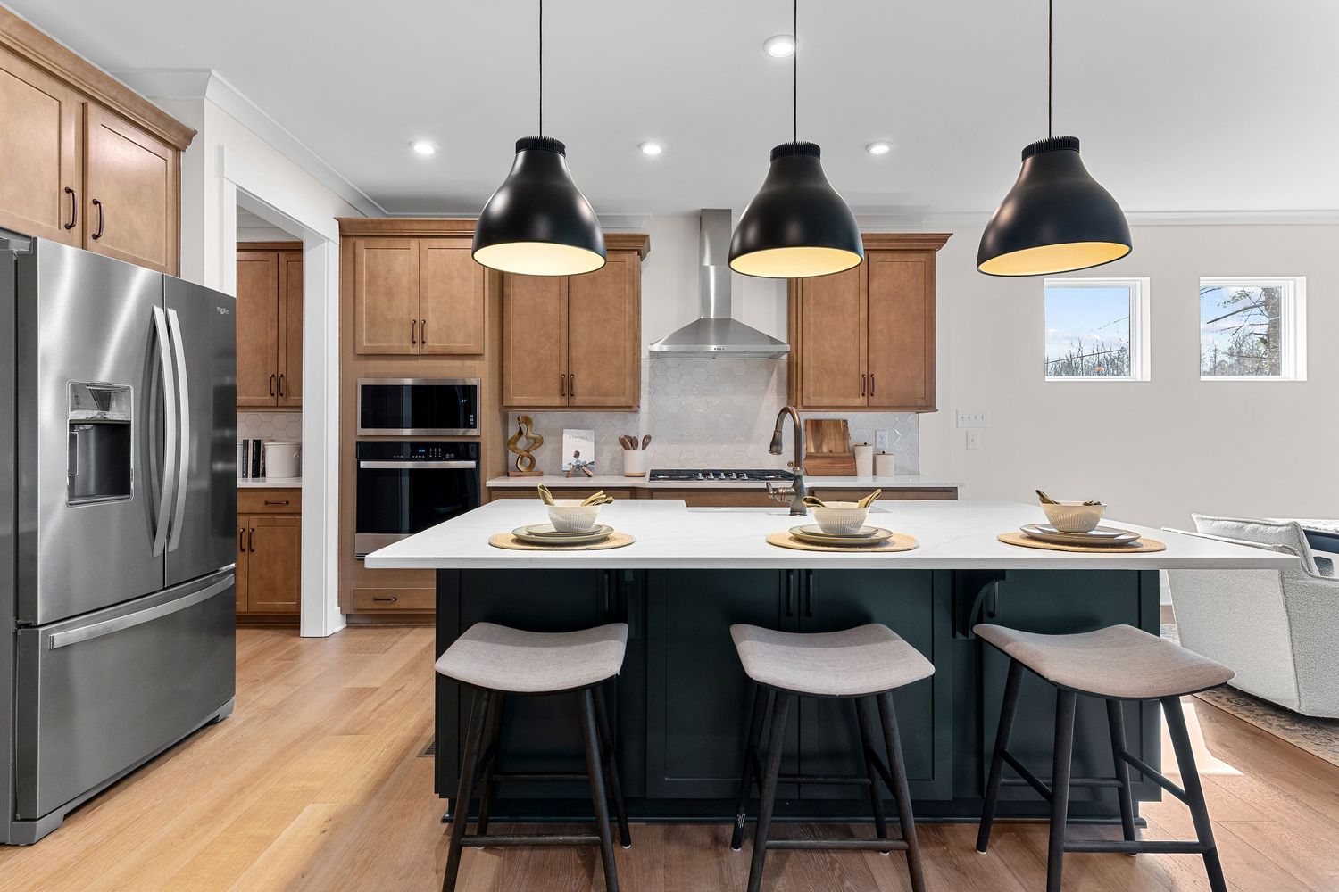 Modern open concept kitchen with wood cabinets, black pendant lights, and a large center island with bar seating.