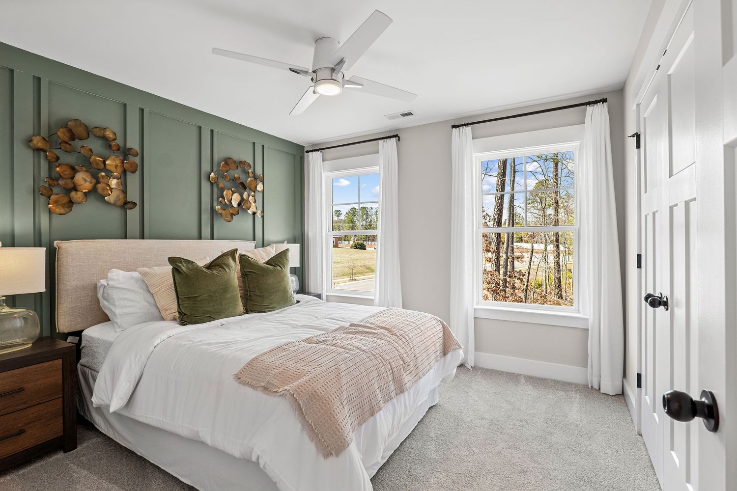 Serene bedroom featuring sage green walls, white bedding, and natural light from windows.