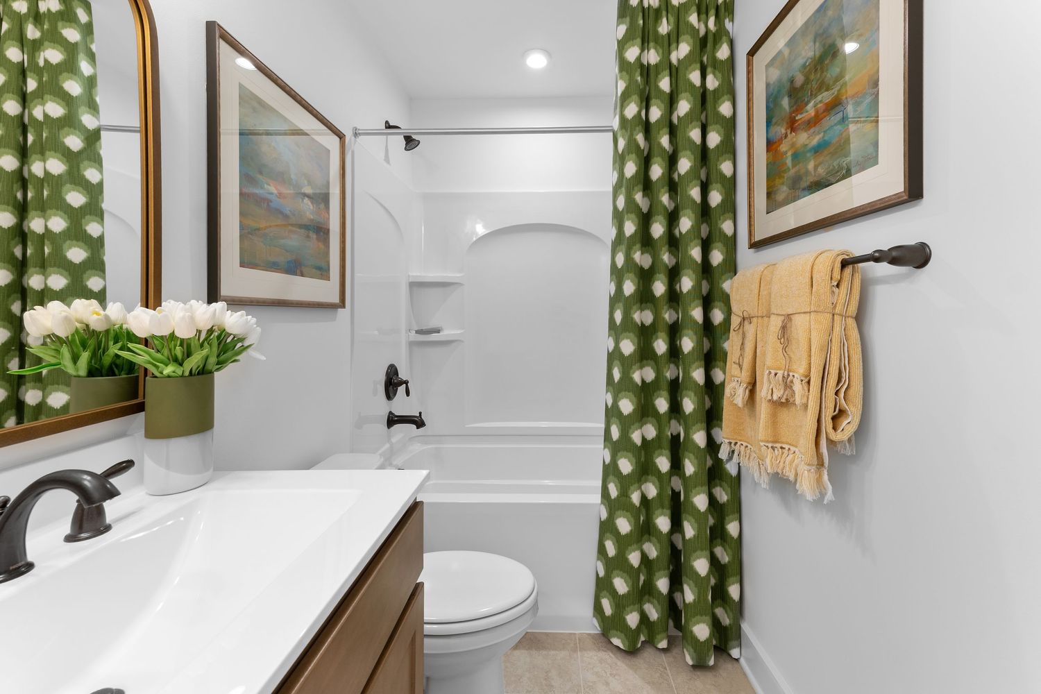 Modern bathroom with green leaf patterned curtains, white walls, and black fixtures showcases a clean contemporary design.