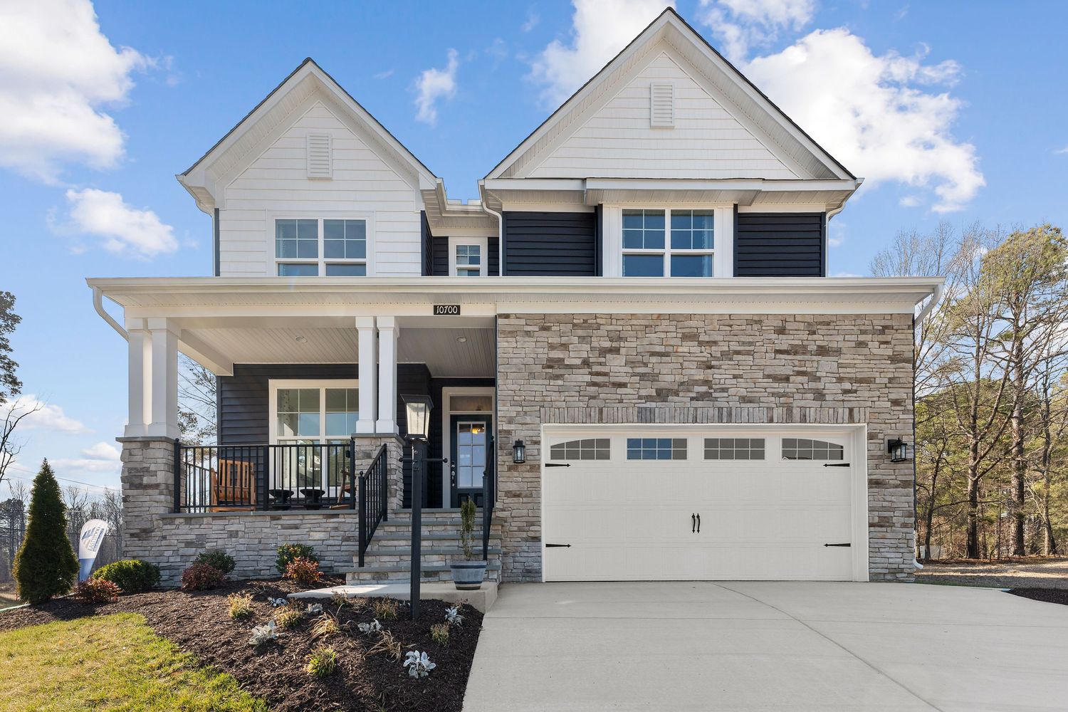 A series of modern suburban homes with stone accents, garages, and white siding showcased against blue skies.