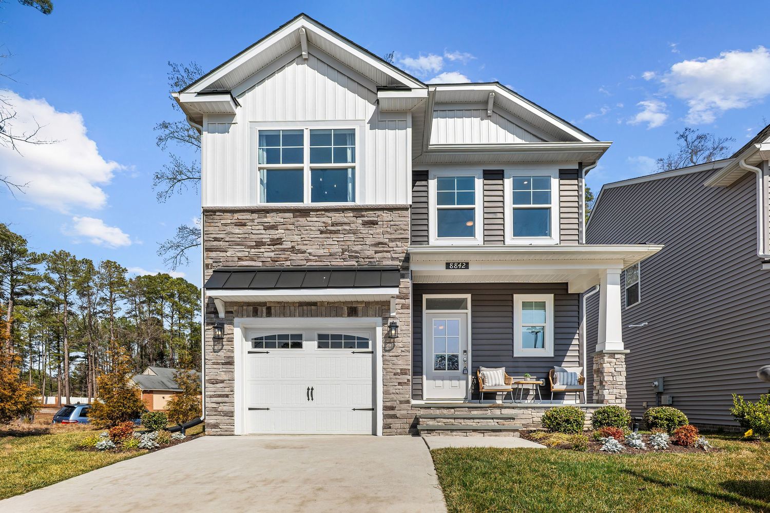 Modern two-story home exterior with stone accents, white siding, and attached garage.