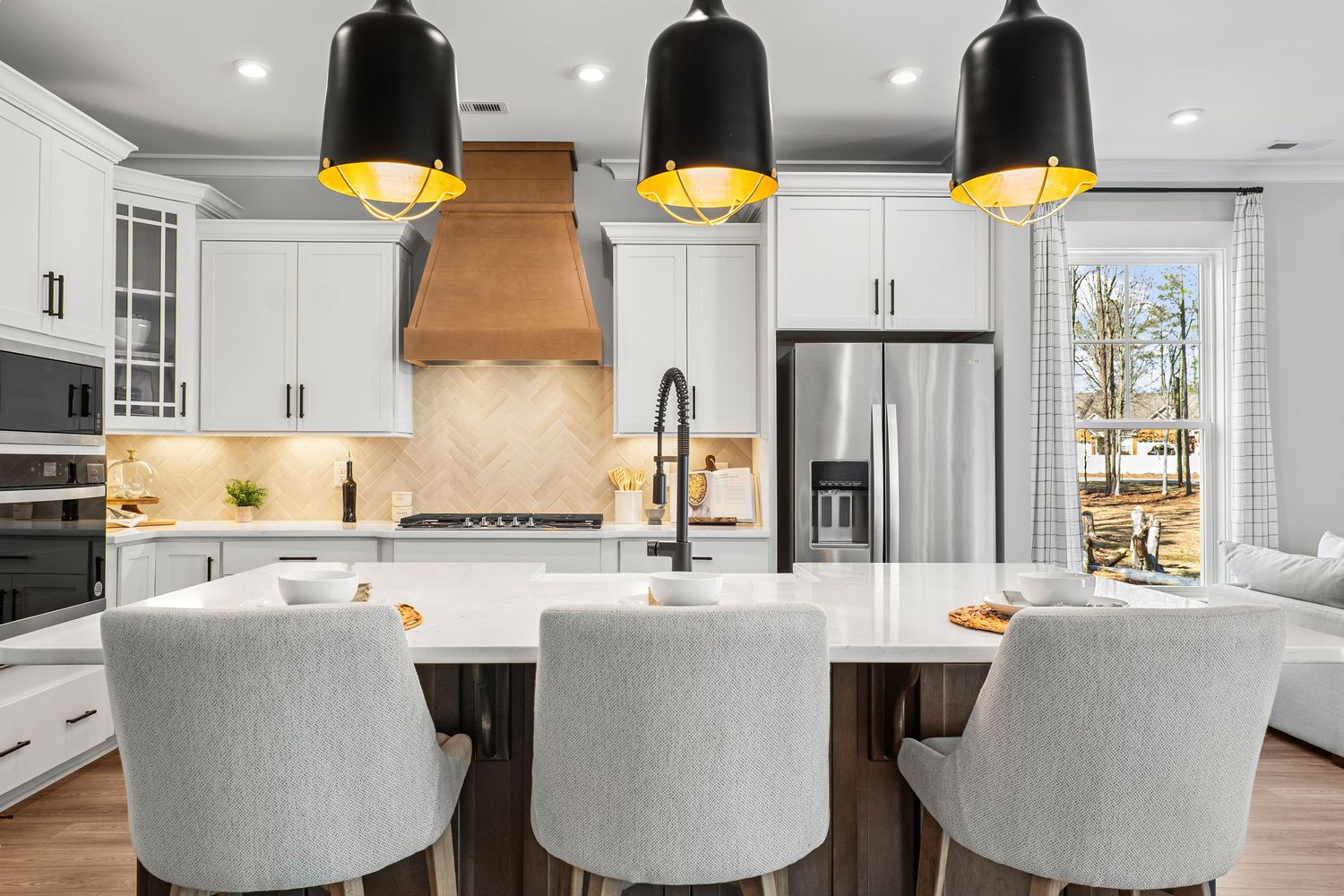 Luxurious kitchen featuring gold pendant lights, white cabinetry, and comfortable bar seating.