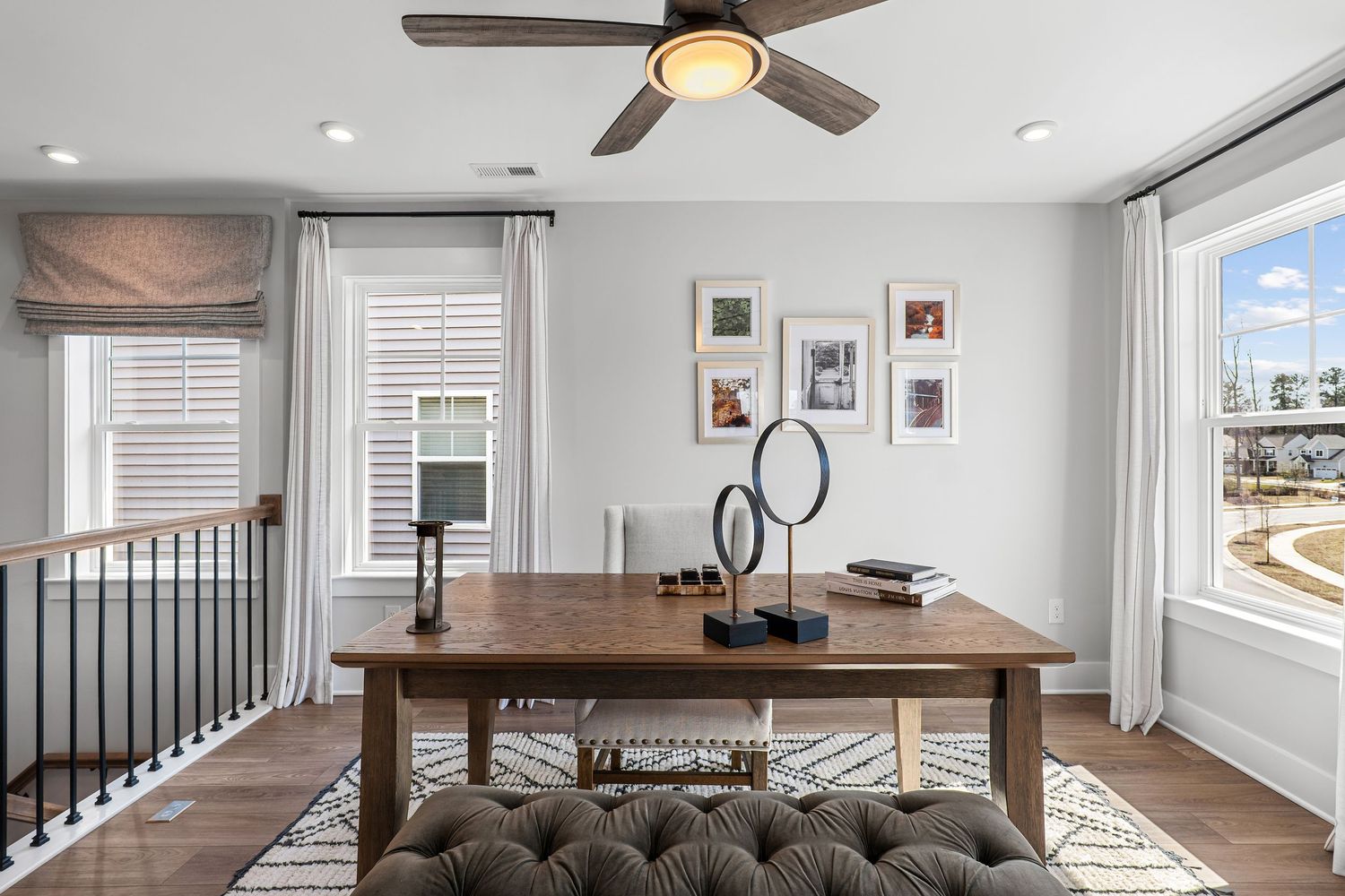 Bright hallway with ceiling fan, hardwood floors and white walls featuring modern decor.