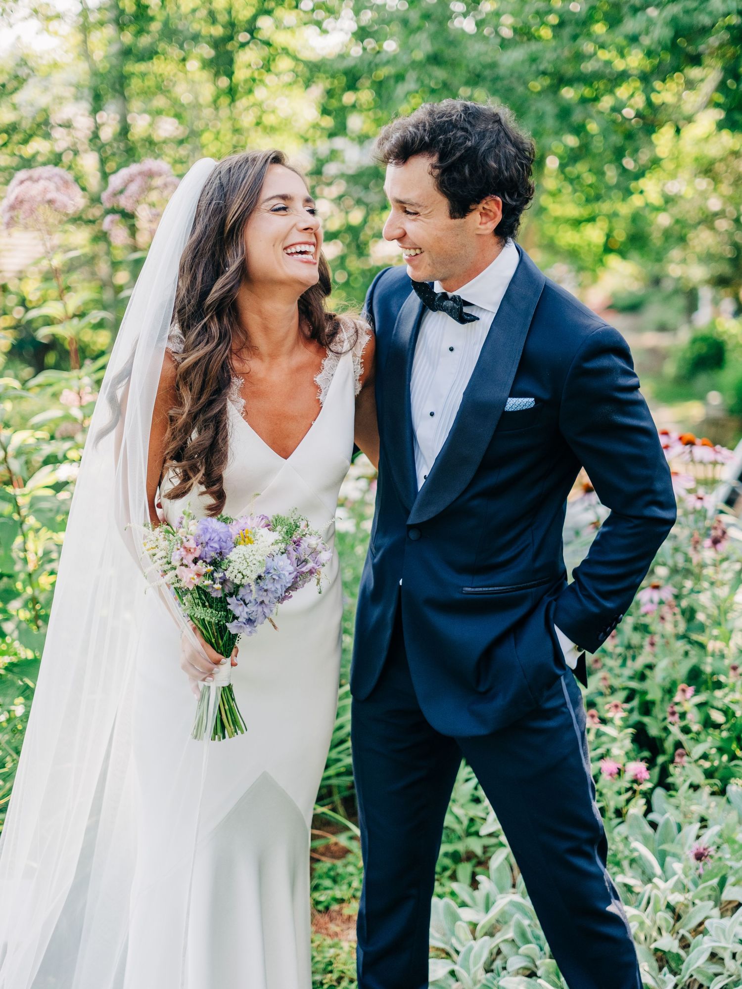 A romantic wedding portrait of a couple laughing together in a lush garden setting.