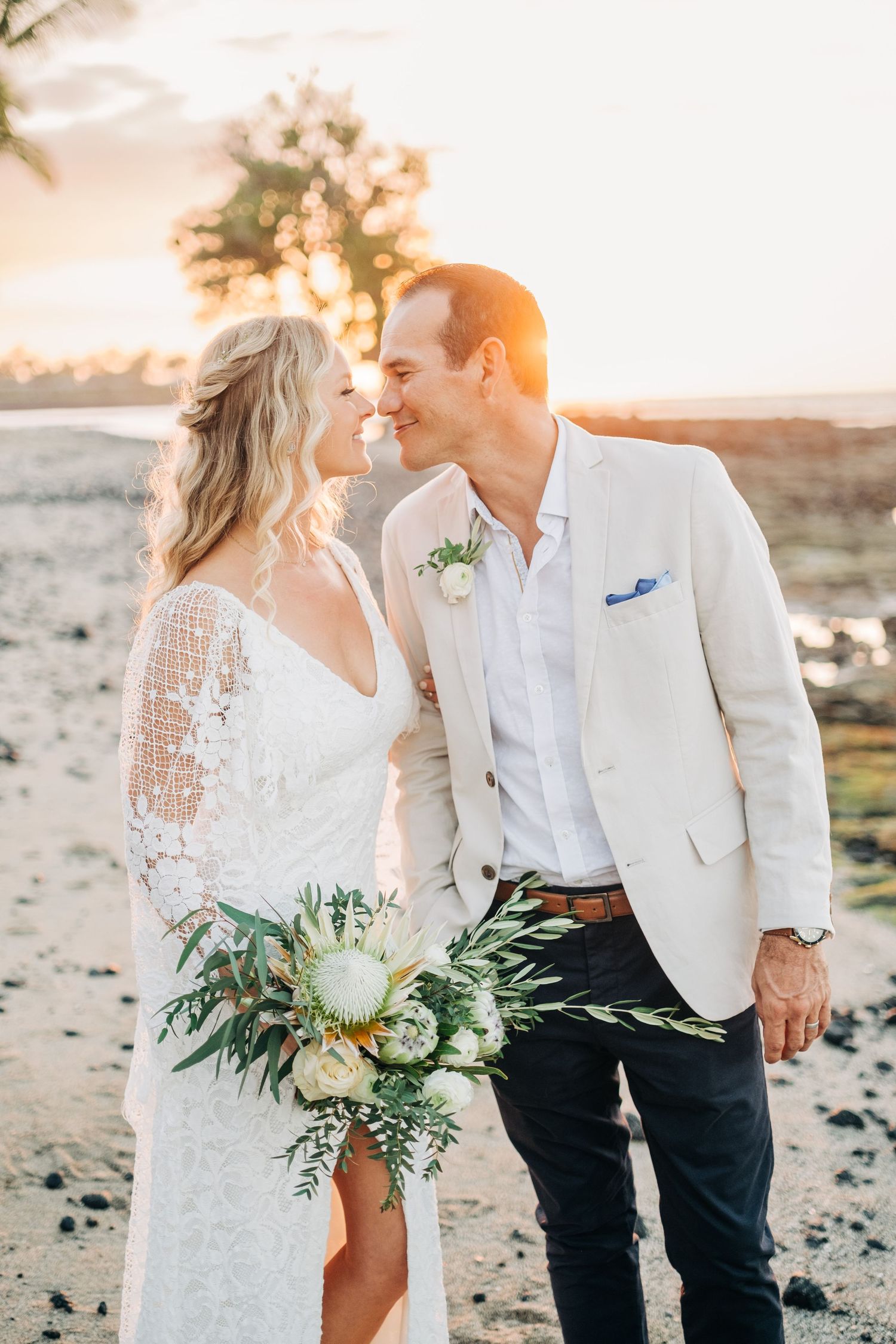 Romantic beach wedding portrait with lush tropical bouquet at golden hour at Mauna Lani Beach Resort.