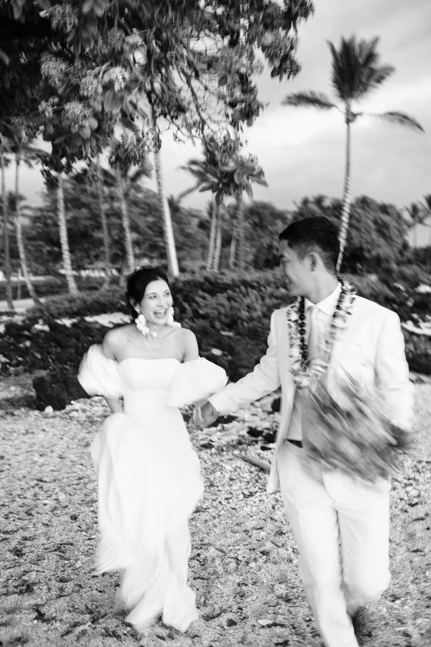 Playful black and white beach portraits with palm trees in the background at Kikaua Point Beach, Big Island of Hawaii.