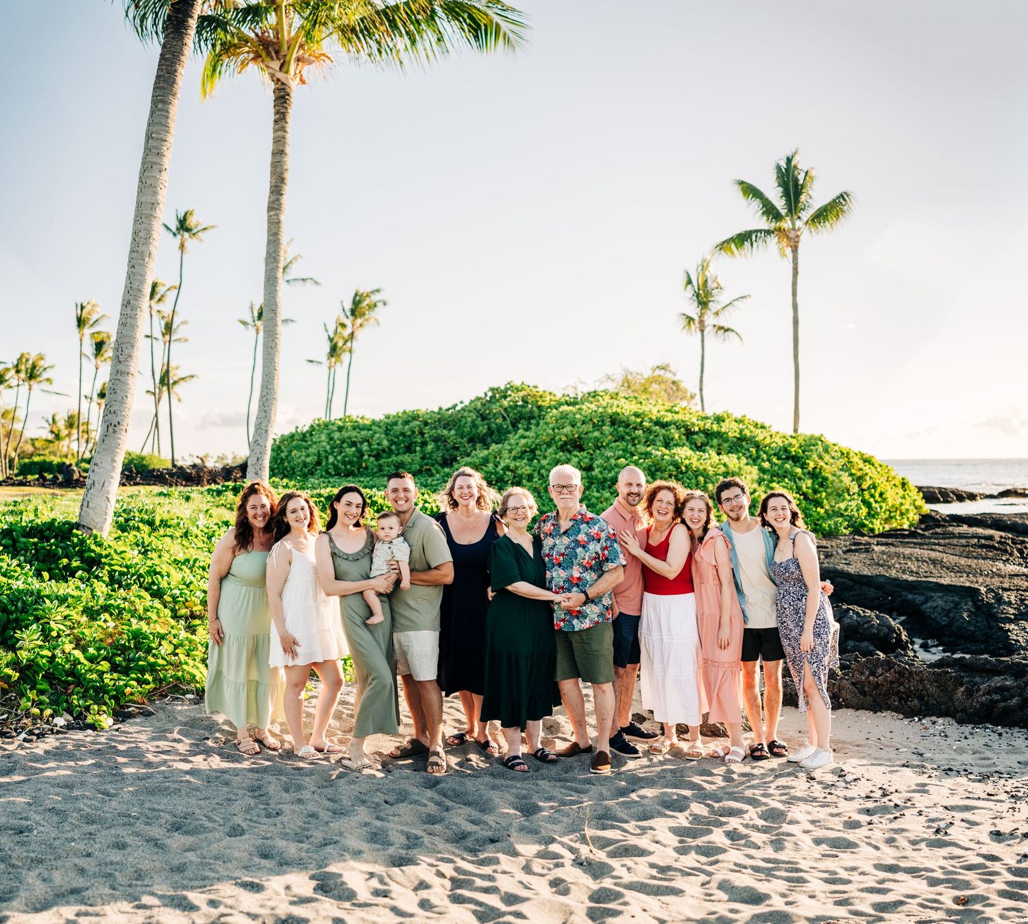 Large group photo of people gathered on tropical beach with palm trees at sunset at Mauna Lani, Big Island of Hawaii.
