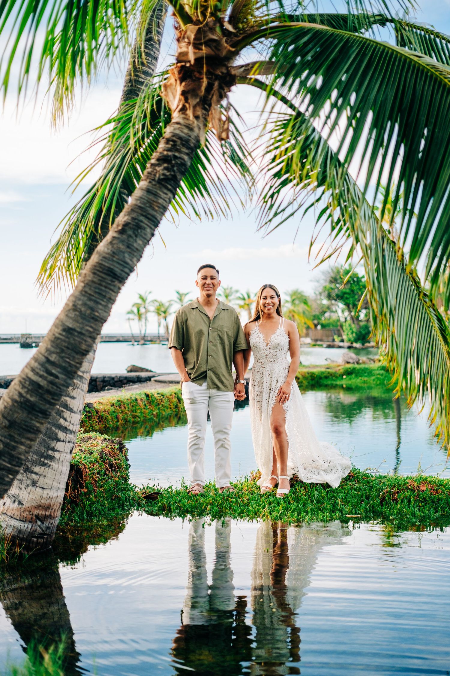 Tropical waterfront photo session with palm trees framing a serene lagoon view at Mauna Lani, Big Island Hawaii.